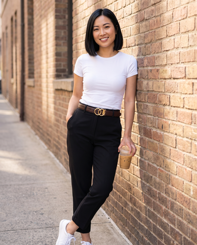Petite woman on a city street wearing a mahogany Halo belt with black trousers